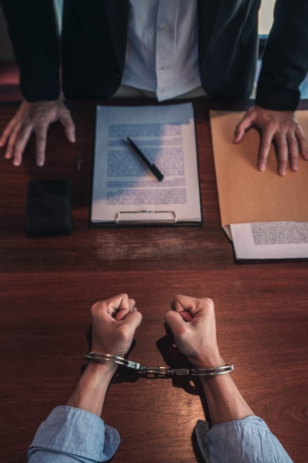 suspect with handcuffs being interviewed in interrogation room by Police officer, Criminal law concept