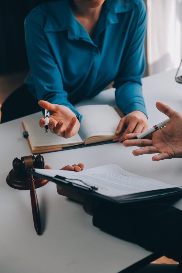 Justice and Law concept. Legal counsel presents to the client a signed contract with gavel and legal law or legal having team meeting at law firm in background